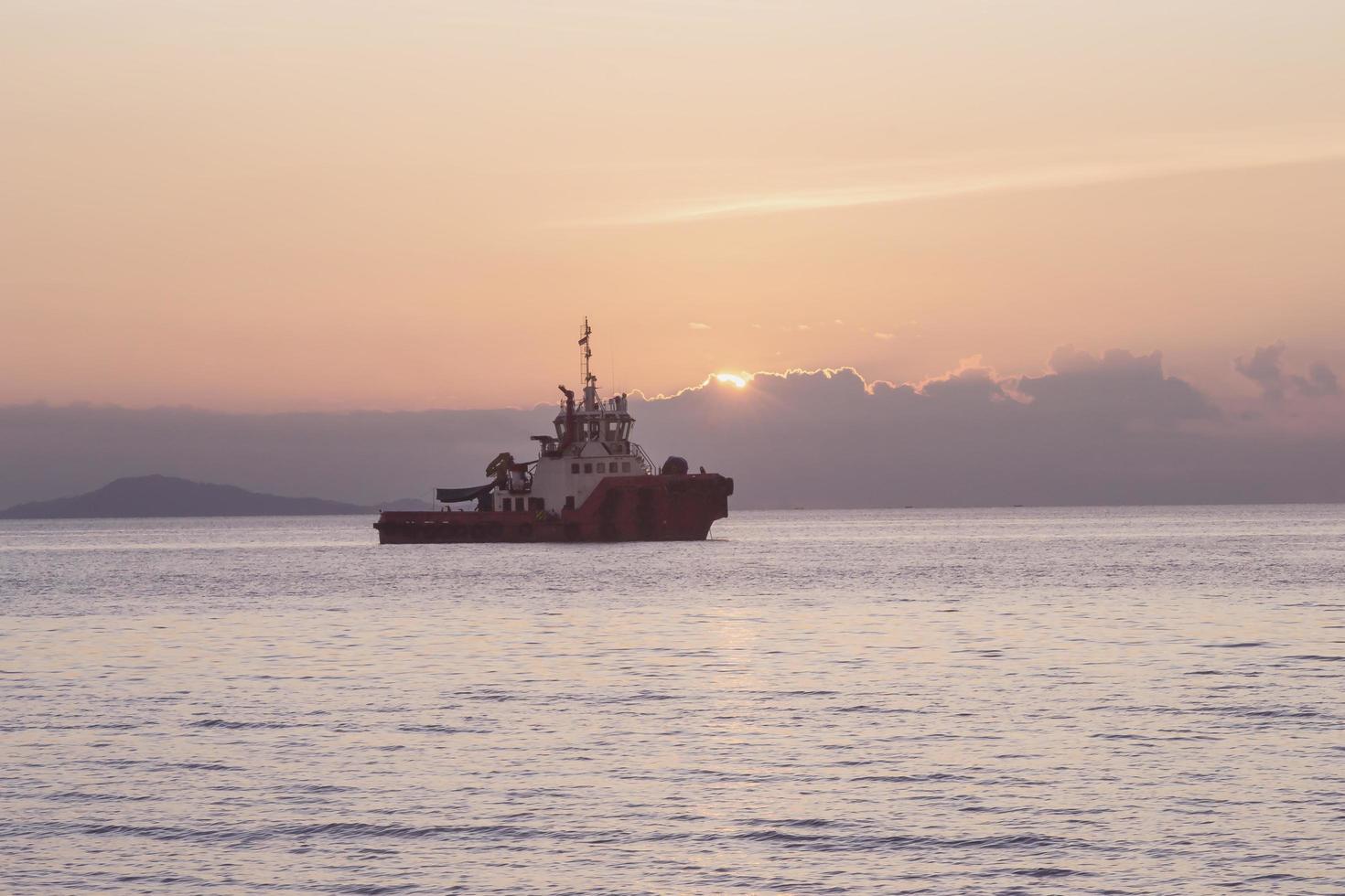 der Sonnenunterganghimmelhintergrund mit Schiffssilhouette, die am Meer festmacht foto