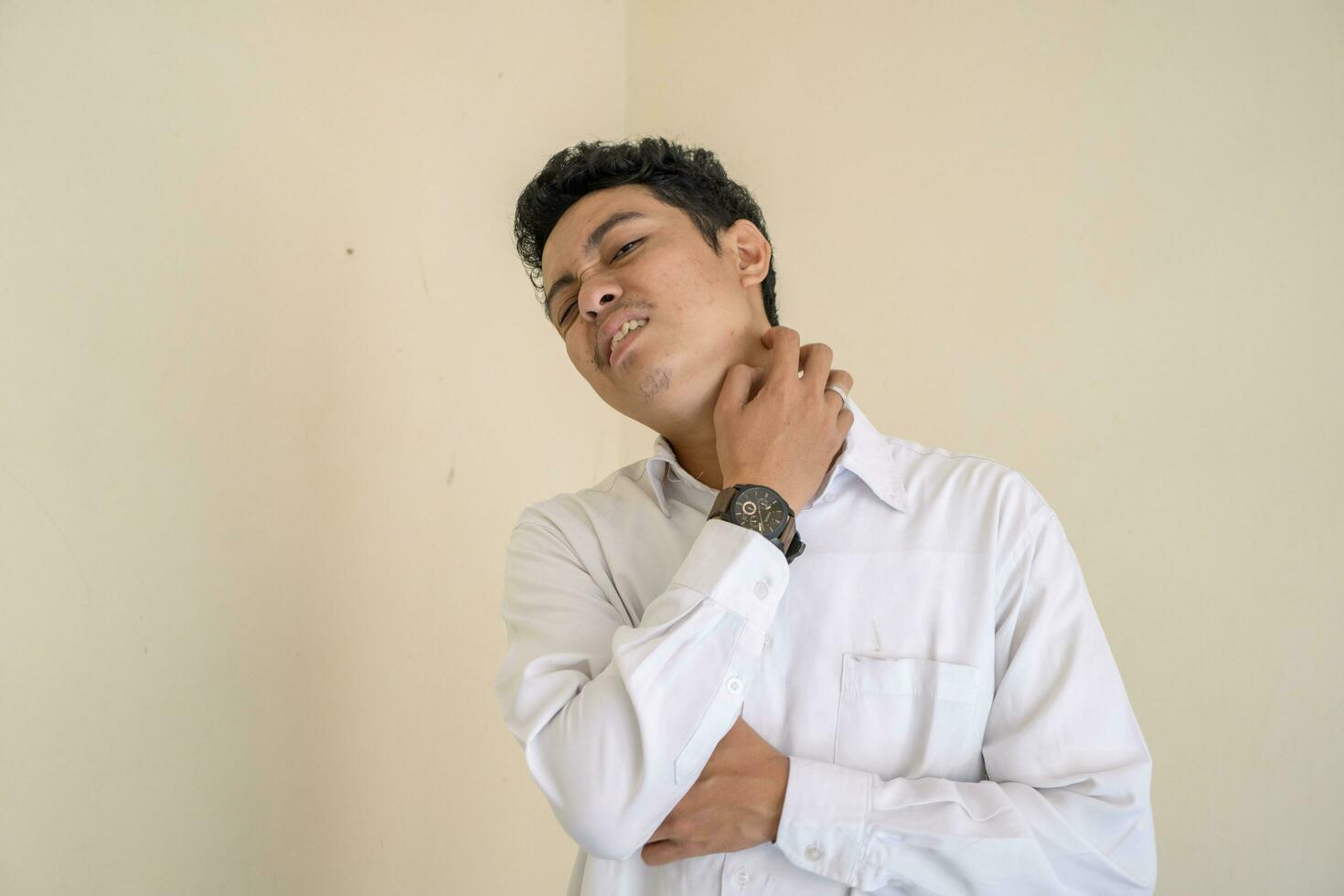 jung indonesisch lockig Mann tragen Weiß Kleider mit Gefühl juckend. foto