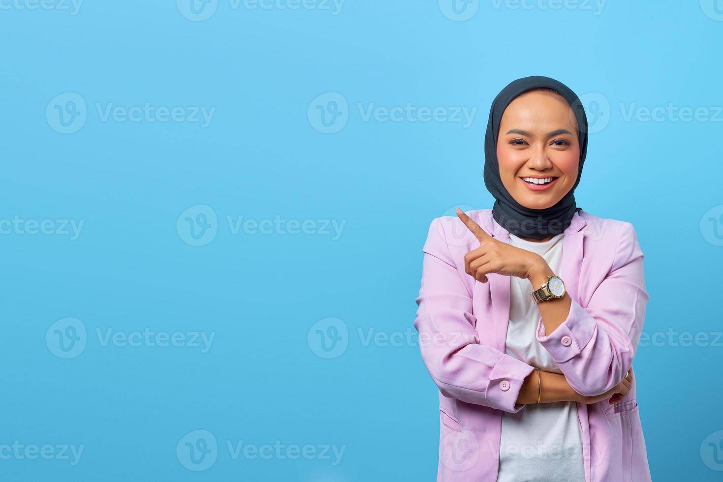 fröhliche asiatische frau, die mit den fingern auf den leeren raum zeigt foto