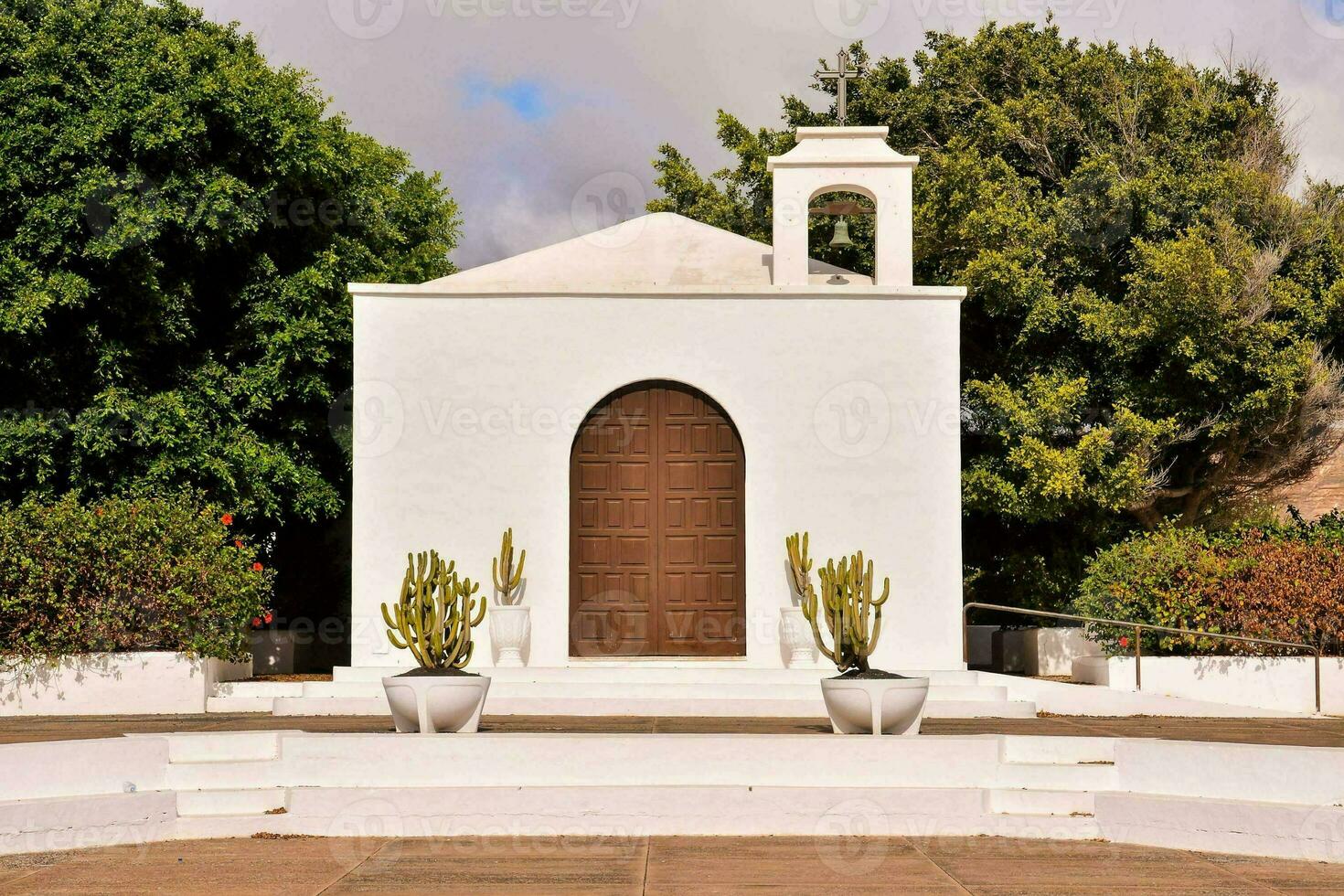 ein Weiß Kirche mit Kaktus Pflanzen im Vorderseite von es foto