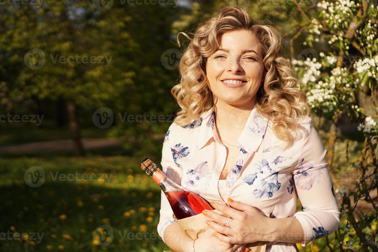 schöne junge frau, die eine leere flasche wein hält foto