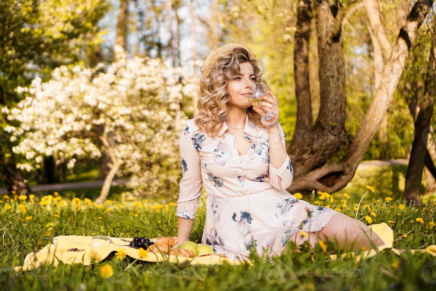 schöne junge frau mit blonden haaren in strohhut trinkt wein foto