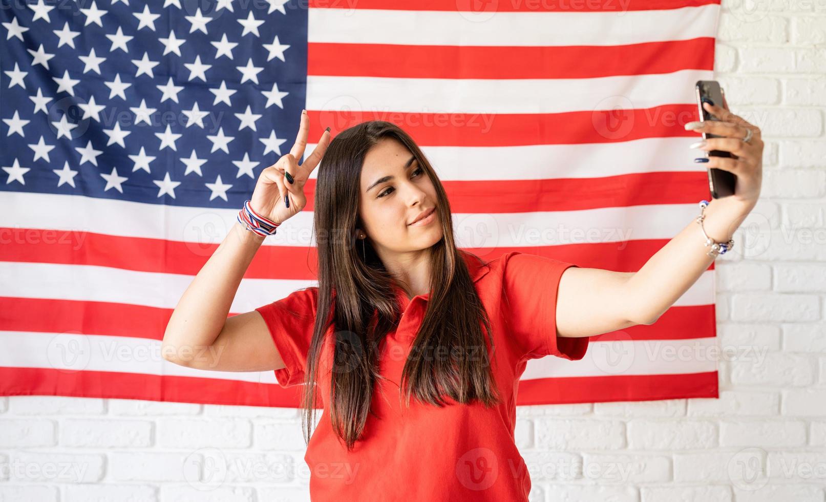 schöne frau, die ein selfie auf dem hintergrund der usa-flagge macht foto