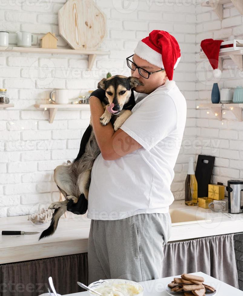 hübscher Hipster mit seinem Hund, der Weihnachtskuchen in einer Küche kocht. foto