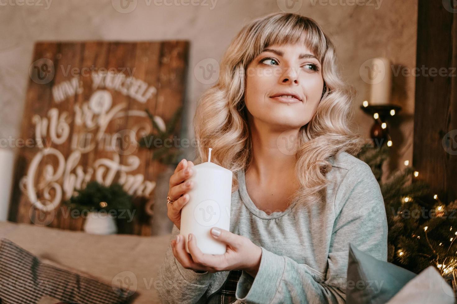 junge Frau, die lächelt, während sie eine Kerze hält, die Weihnachten feiert foto