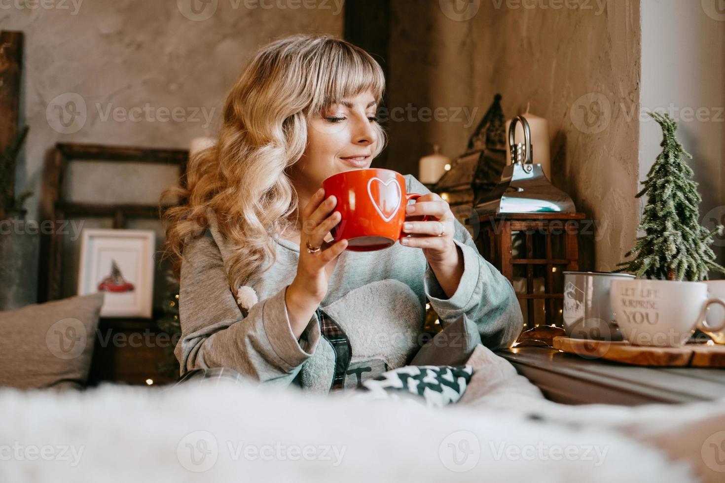 junge Frau mit Tasse Tee im gemütlichen Weihnachtsinterieur foto