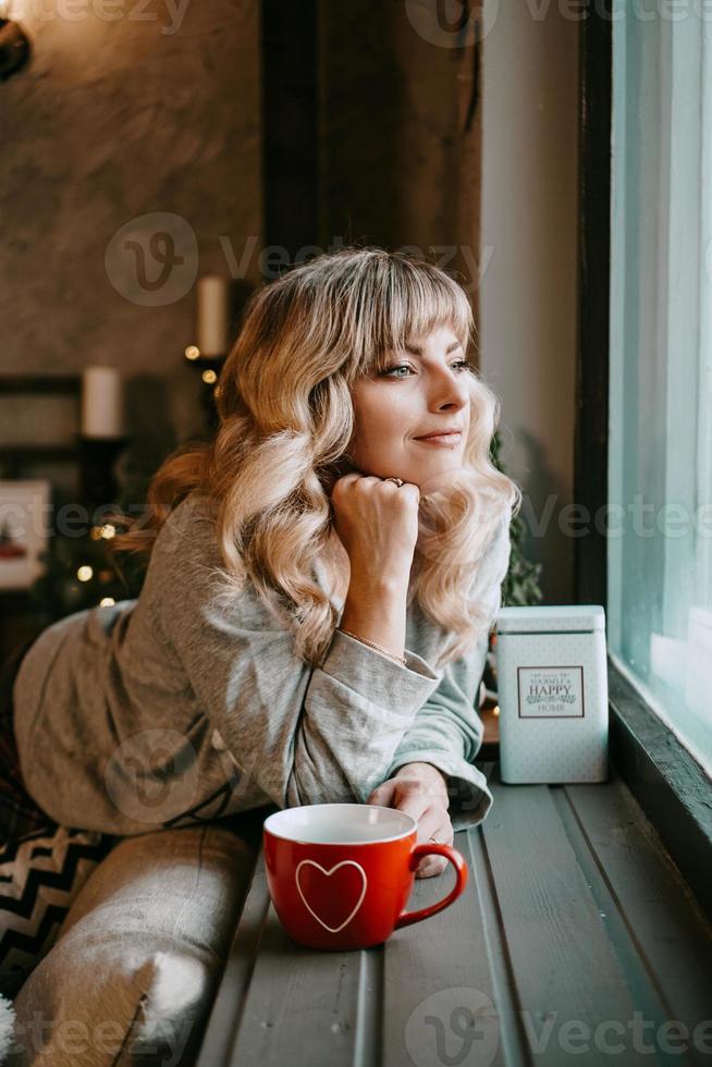 junge Frau mit Tasse Tee im gemütlichen Weihnachtsinterieur foto