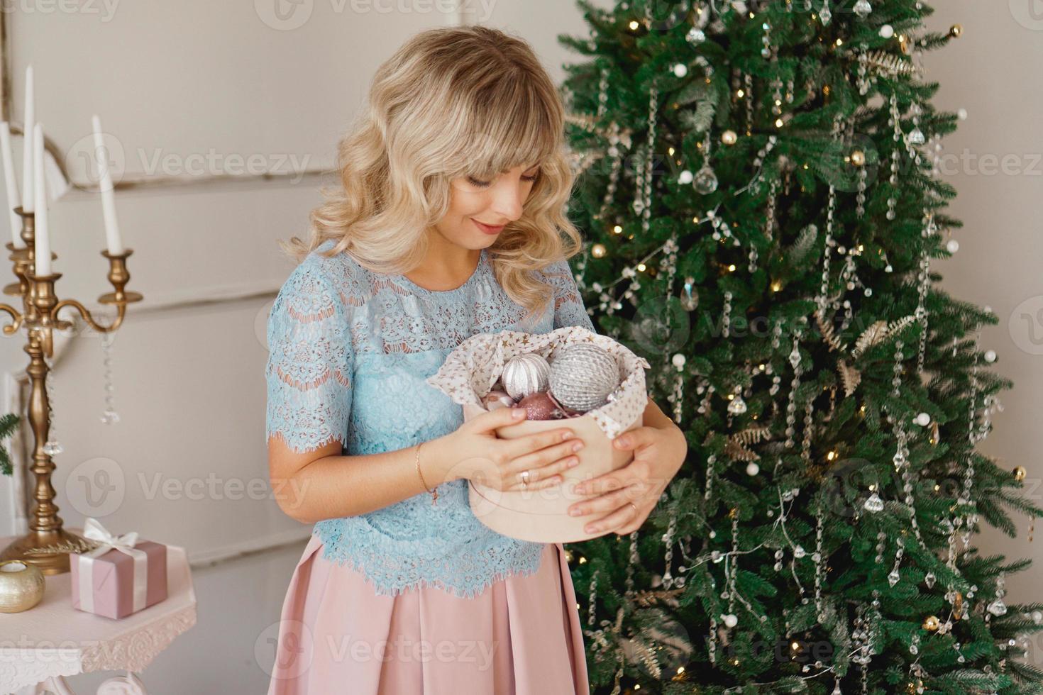 junge Frau schmückt Weihnachtsbaum mit Weihnachtsspielzeug foto