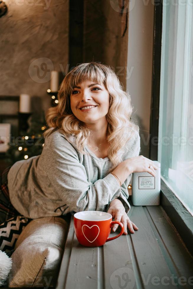 junge Frau mit Tasse Tee im gemütlichen Weihnachtsinterieur foto