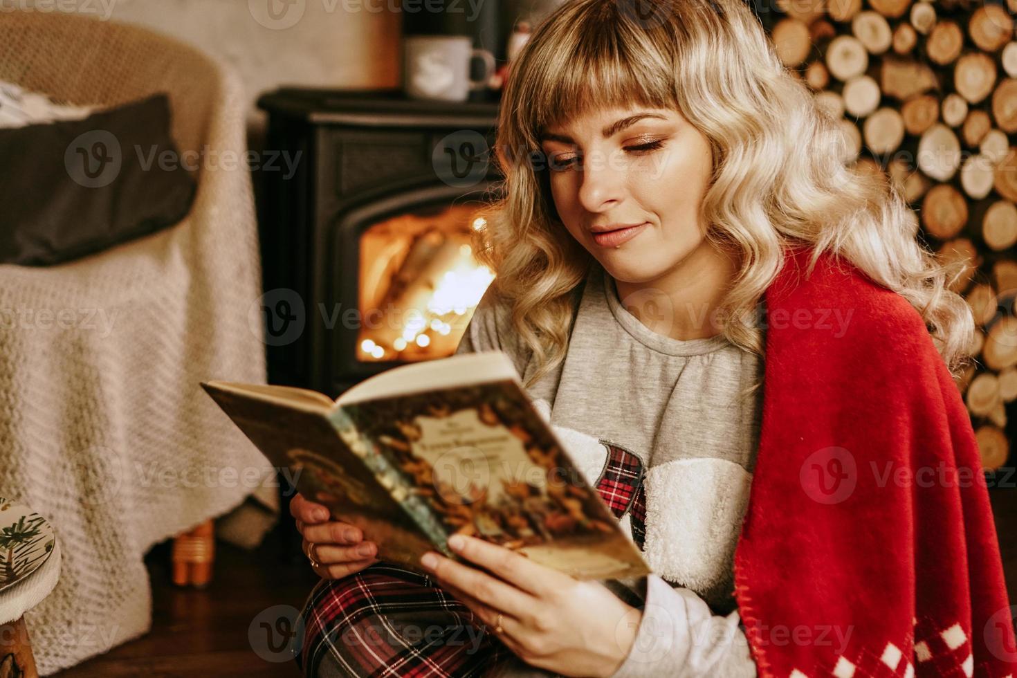 glückliche junge frau, die buch vor weihnachtsinnenraum liest foto