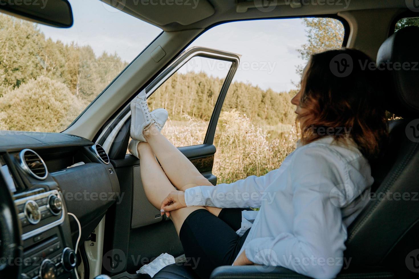 die Frau im Auto auf dem Beifahrersitz. Füße aus dem Fenster. foto