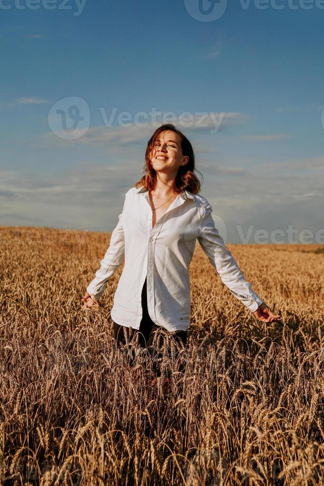 glückliche junge Frau in einem weißen Hemd in einem Weizenfeld. sonniger Tag. foto