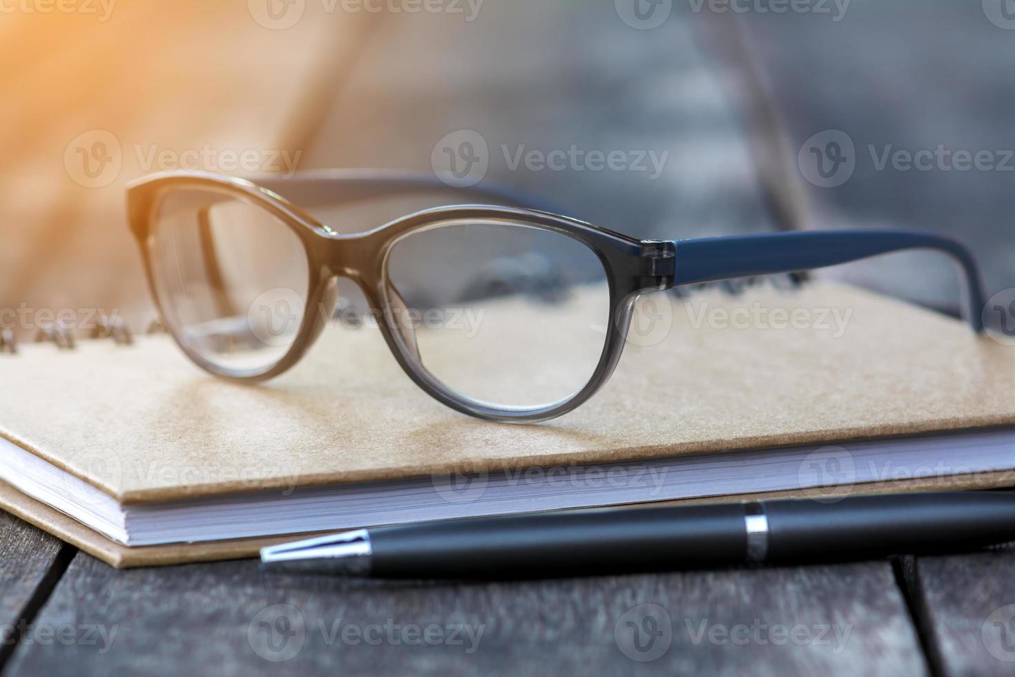 Brille auf Notizbuch mit Stift und Holzhintergrund foto