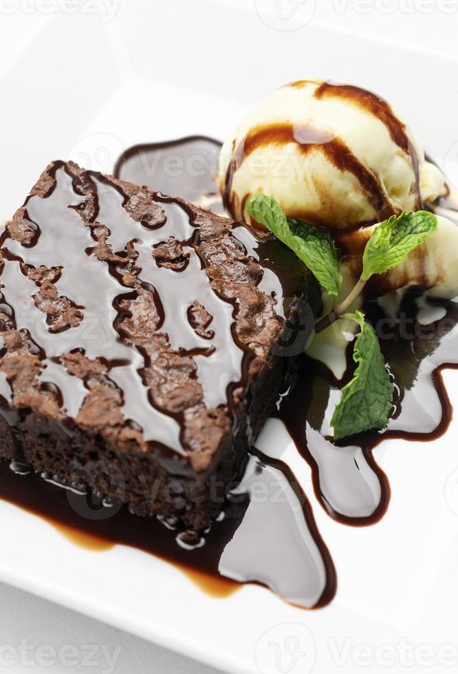 veganes Schokoladen-Brownie-Dessert mit milchfreiem Kokosmilch-Vanilleeis mit Karamellsauce auf weißem Hintergrund im Studio foto