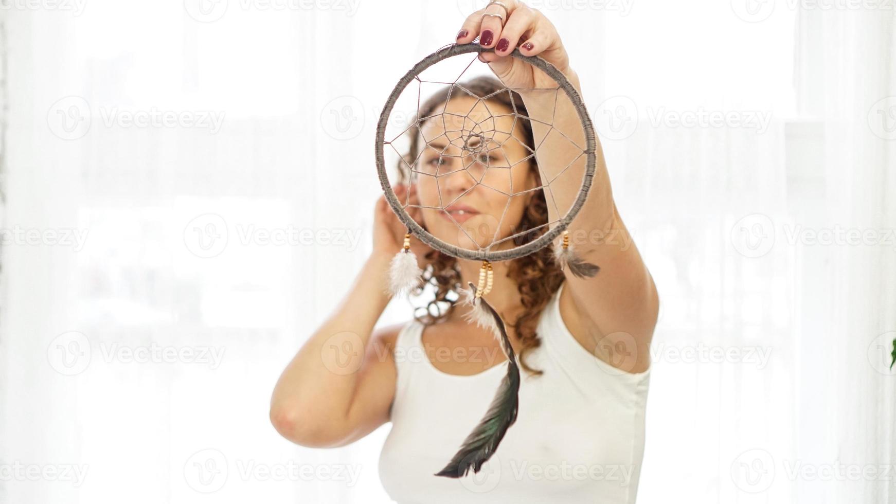 Frau mit lockigem Haar mit Traumfänger in der Hand foto