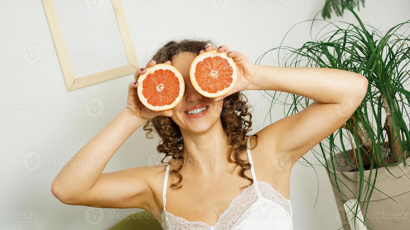 Porträt einer Frau, die ihr Auge mit Grapefruit bedeckt foto