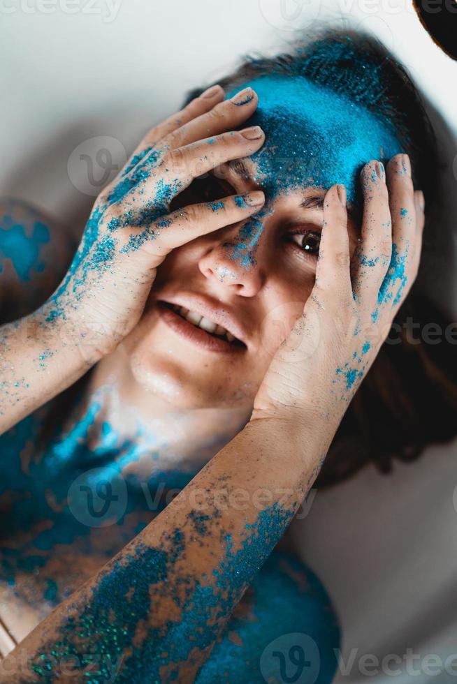 Frau mit Funkeln im Gesicht. Mädchen in der Badewanne foto