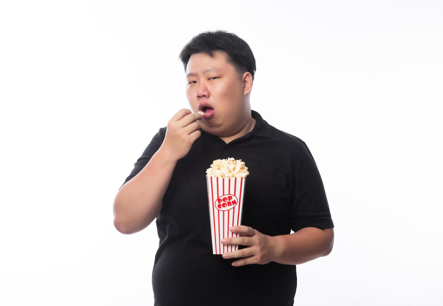 junger lustiger fetter asiatischer Mann, der Popcorn isst foto