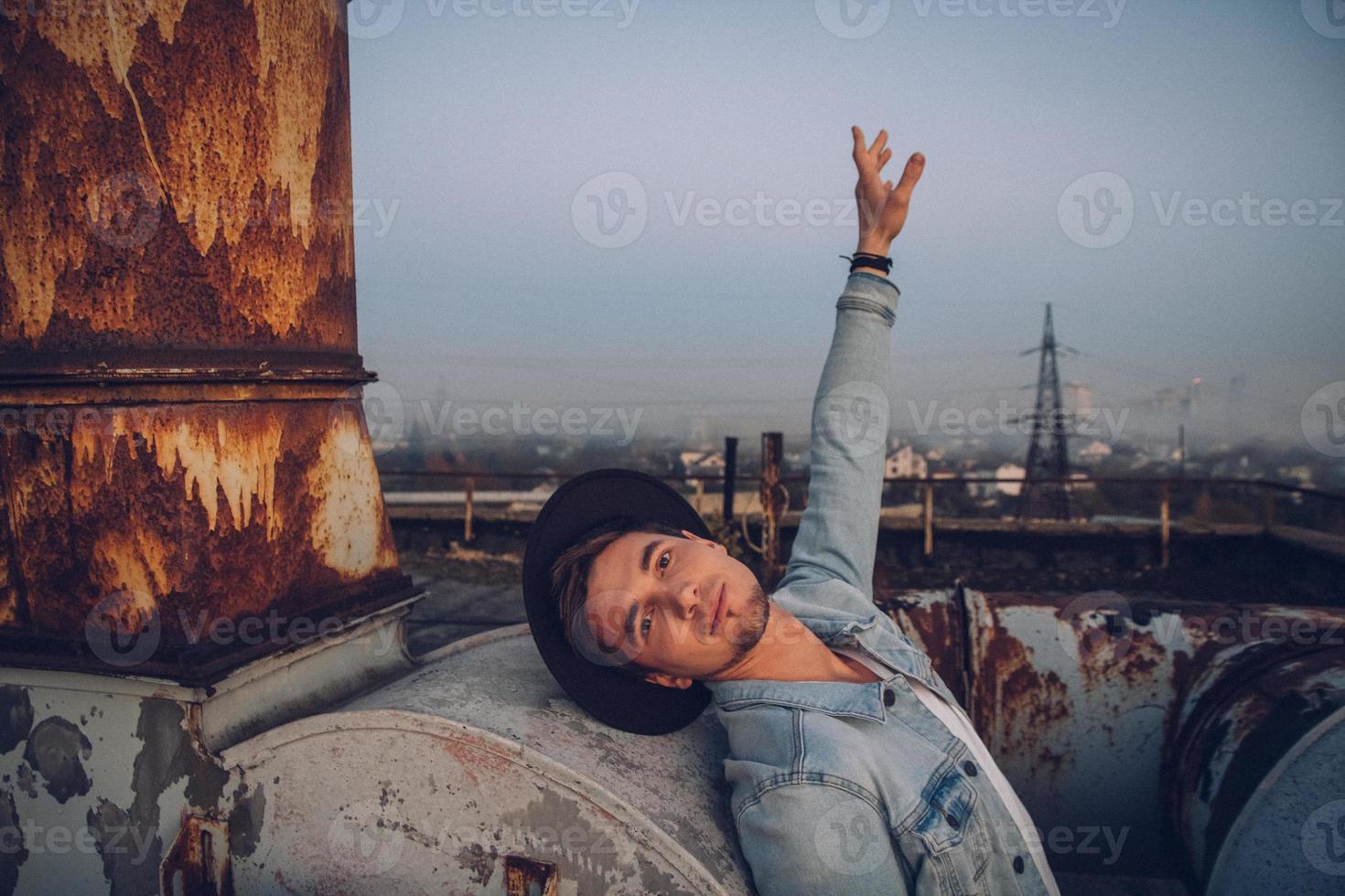 Mann mit Hut trägt weißes Hemd und Jeans im Hintergrund der Stadt foto