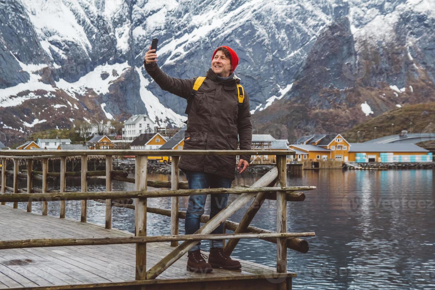 Mann macht Selfie mit Bergen und See hinter sich foto