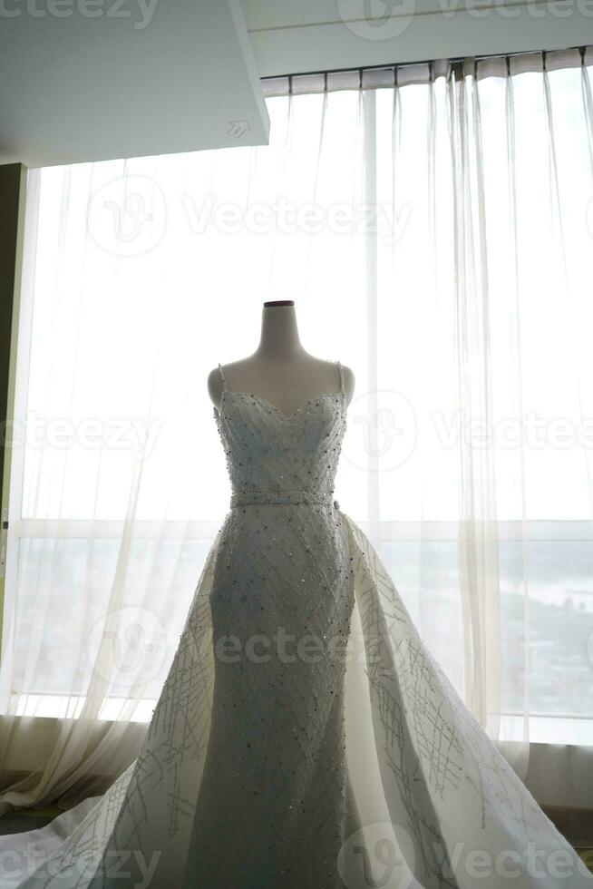 schön Weiß Hochzeit Kleid auf ein Weiß Mannequin im das Zimmer mit groß Fenster foto