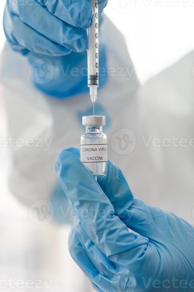 Arzt zieht Covid-19-Impfstoff aus einer Durchstechflasche foto