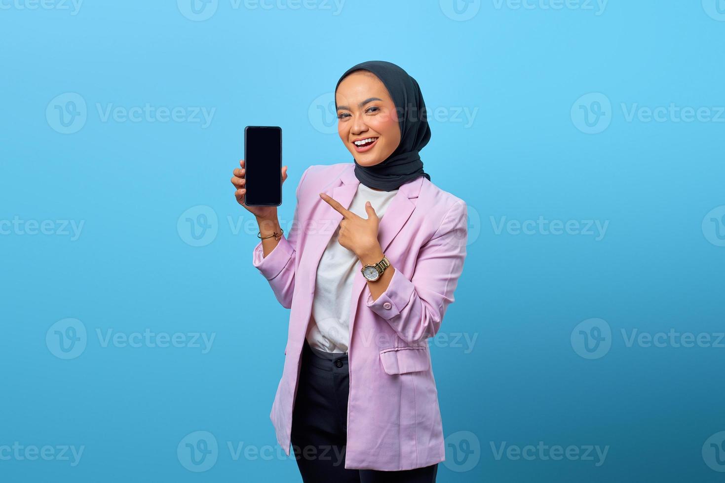 Porträt einer lächelnden asiatischen Frau, die einen leeren Bildschirm des Smartphones zeigt foto