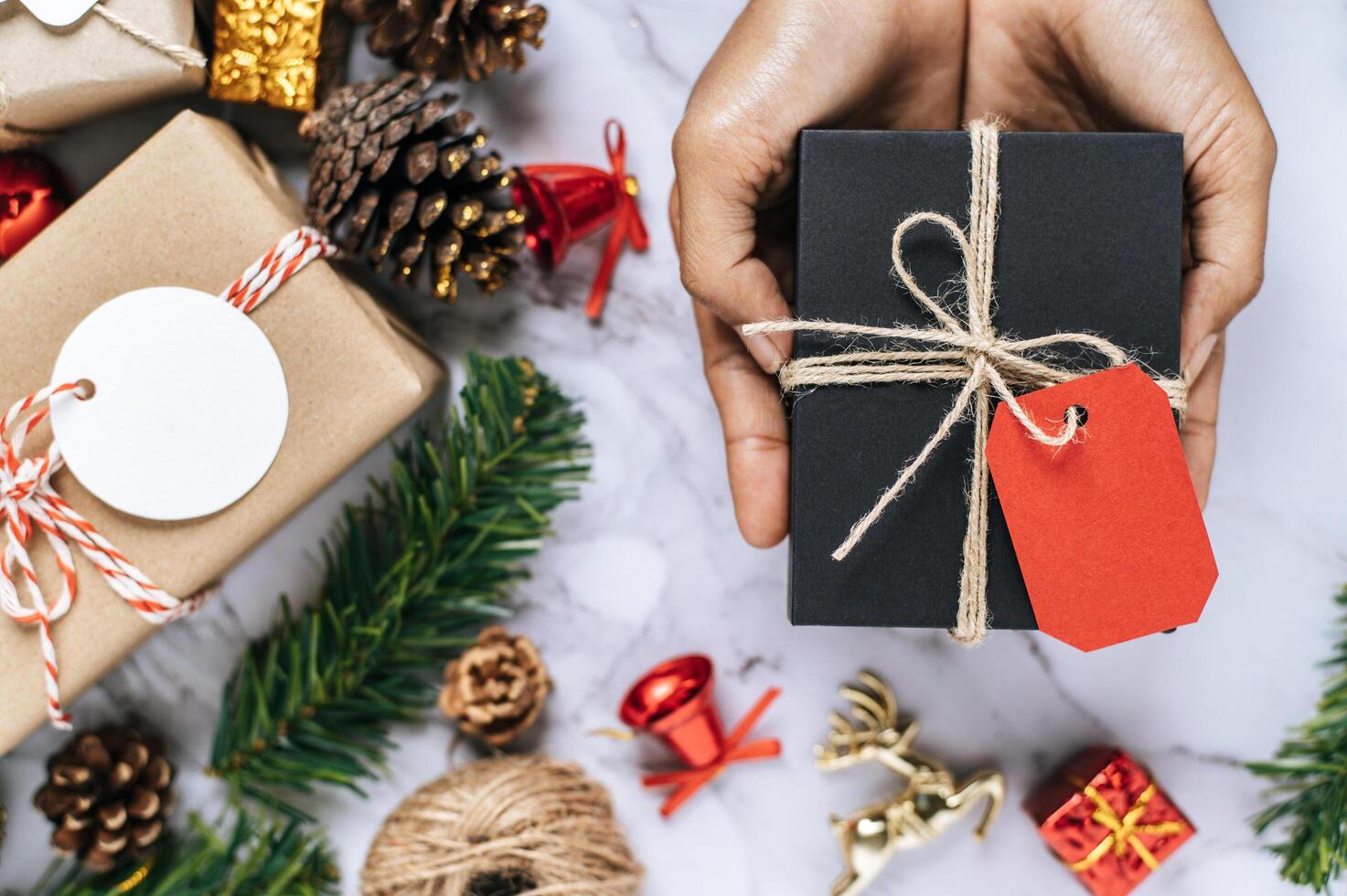 eine Hand, die eine schwarze Geschenkbox auf einem weißen Zementboden hält foto