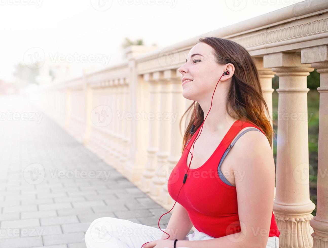 Teenager-Mädchen sitzt neben dem Spaltenfechten und hört die Musik? foto