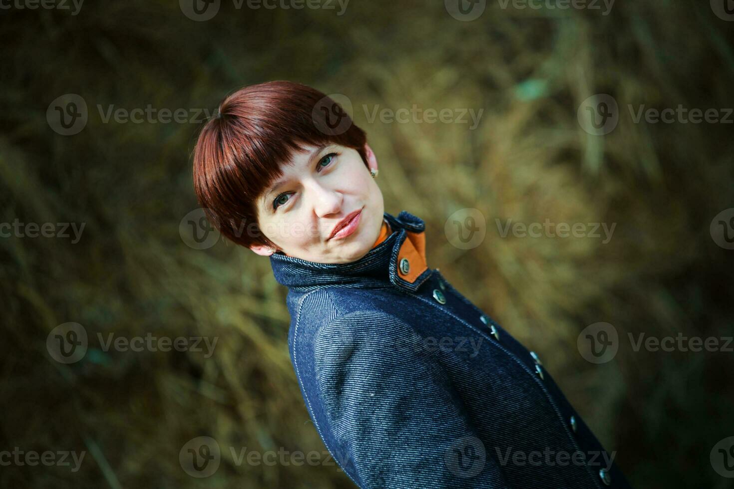 schön Frau mit kurz Haar sieht aus in das rahmen. Porträt von ein dreißig Jahre alt Frau. ein Mädchen im ein stabil im das Hintergrund von Heuhaufen. foto