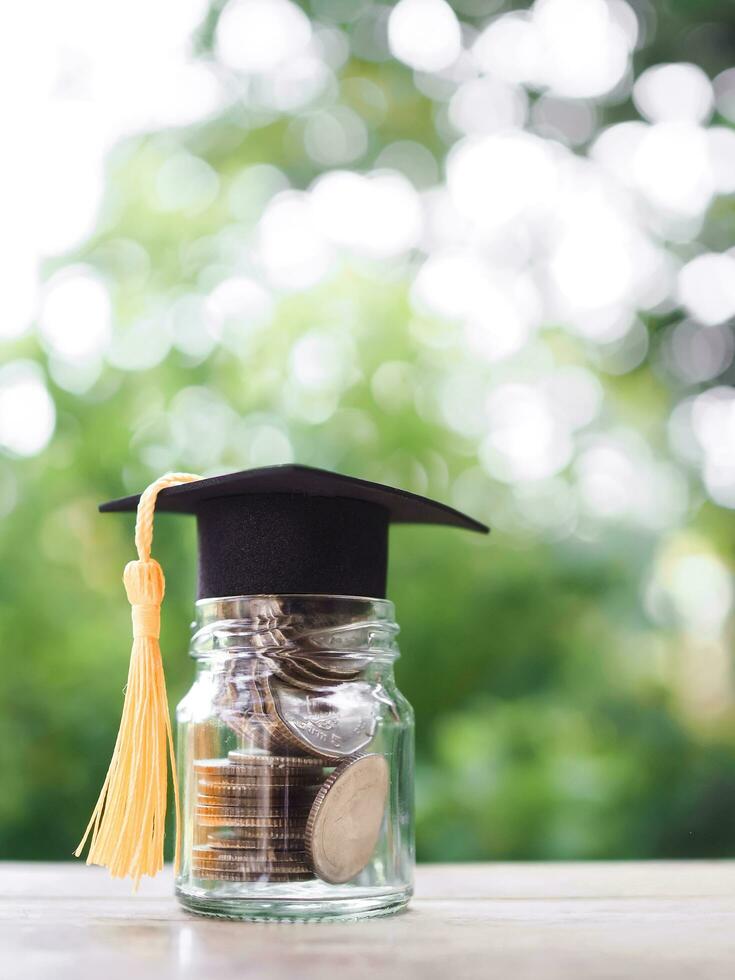 Glas Flasche mit Abschluss Hut. das Konzept von Speichern Geld zum Ausbildung, Schüler Darlehen, Stipendium, Unterricht Gebühren im Zukunft foto