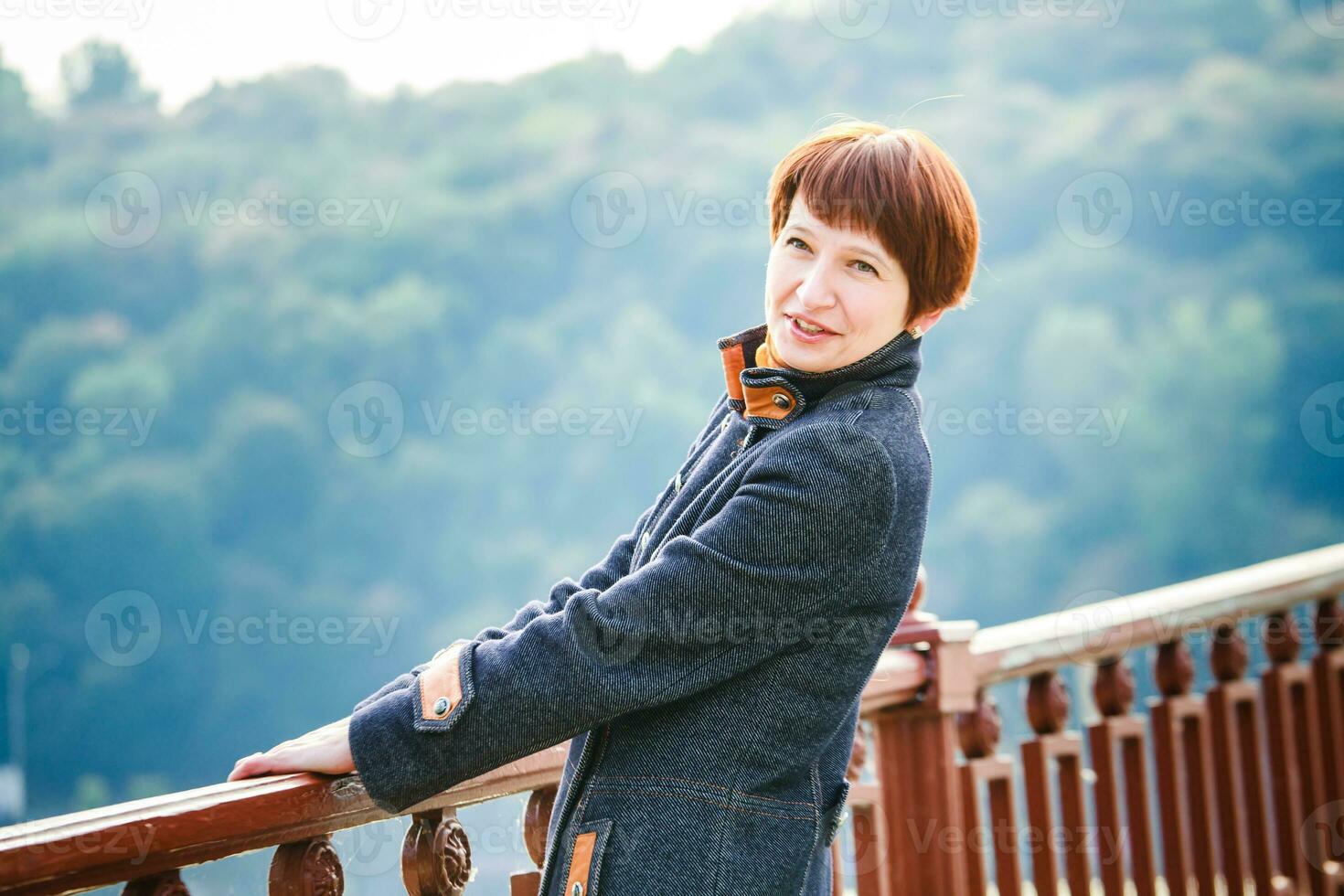 jung Frau Stehen auf ein Fußgänger Brücke im Kiew. das Frau mit kurz Haar gelehnt auf das Brücke Geländer. Frau auf das Hintergrund von Kiew Landschaft. foto