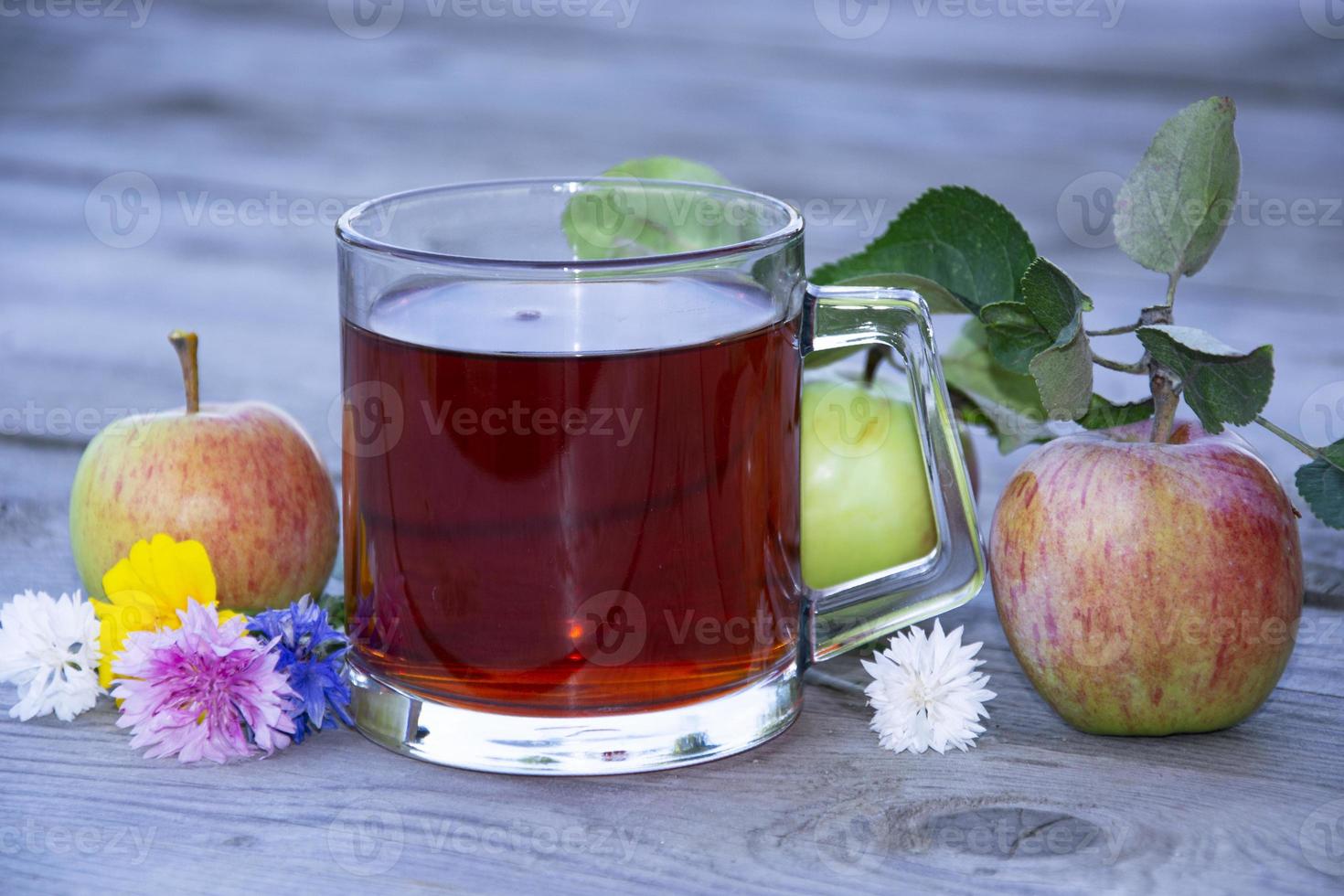 Tasse mit Tee unter Früchten auf einem hölzernen Hintergrund. foto