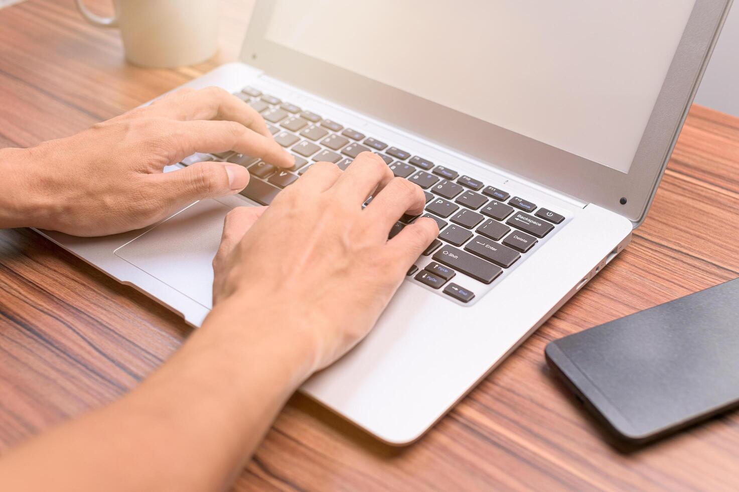 Hand mit Notebook-Computer am Schreibtisch foto