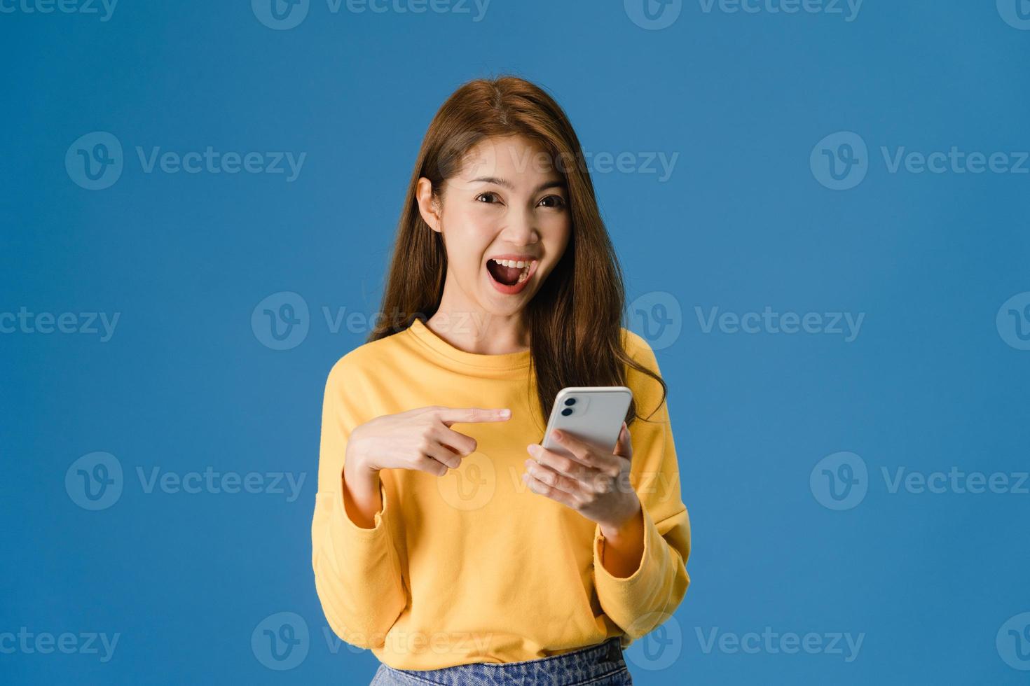 junge Dame mit Telefon mit positivem Ausdruck auf blauem Hintergrund. foto