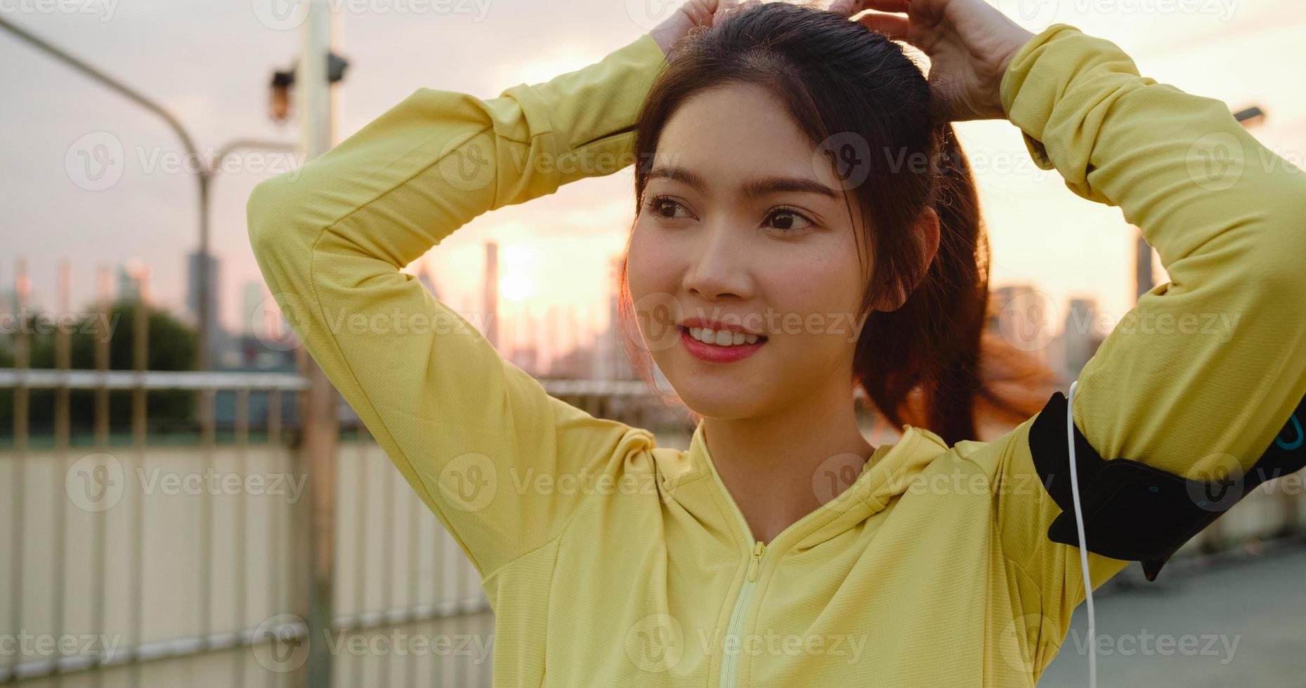 asiatische Sportlerin in gelber Kleidung, die sich auf das Training in der Stadt vorbereitet. foto