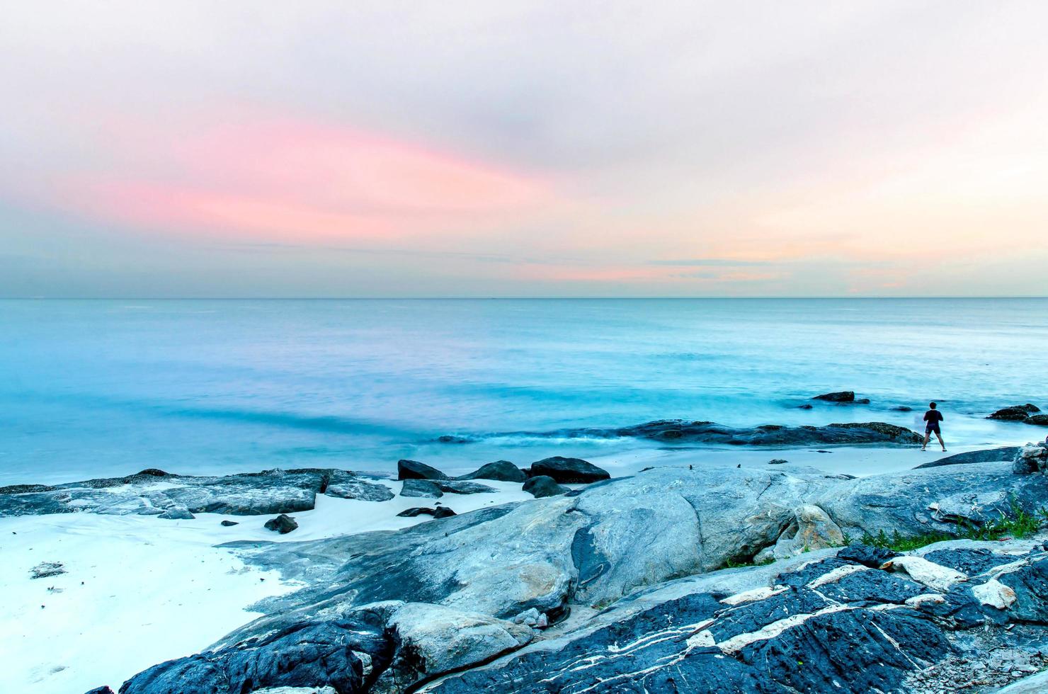 der Blick auf den Sandstrand und die Meereswelle mit Felsen und Riff am Morgen foto