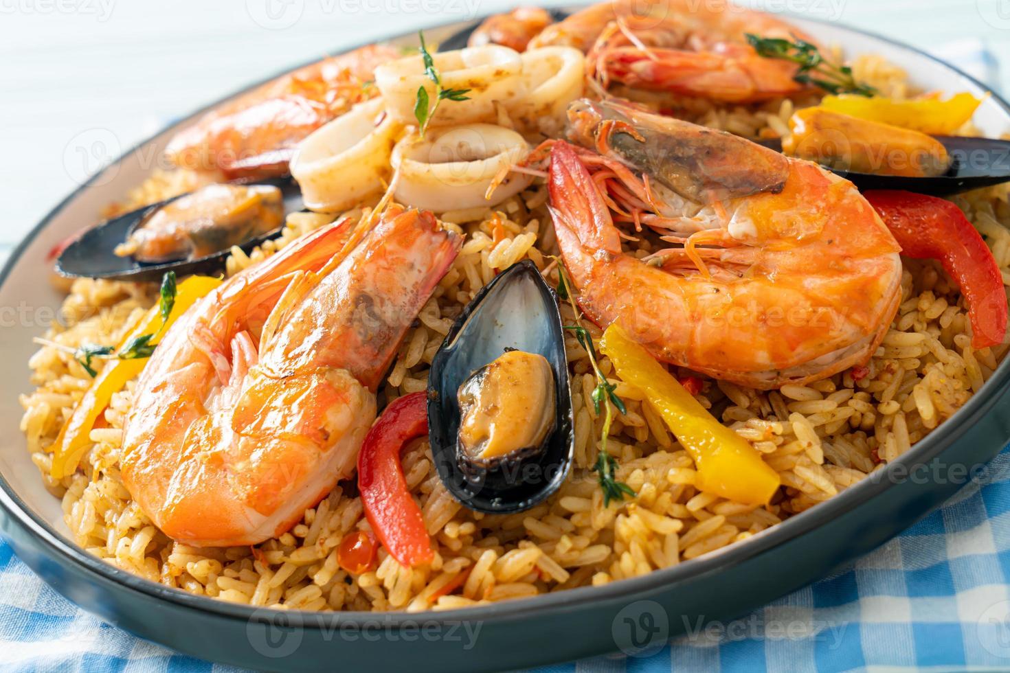 Meeresfrüchte-Paella mit Garnelen, Venusmuscheln, Miesmuscheln auf Safranreis foto