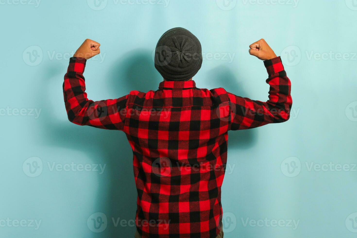 zuversichtlich jung asiatisch Mann Herstellung ein stark Geste, isoliert auf ein Blau Hintergrund foto