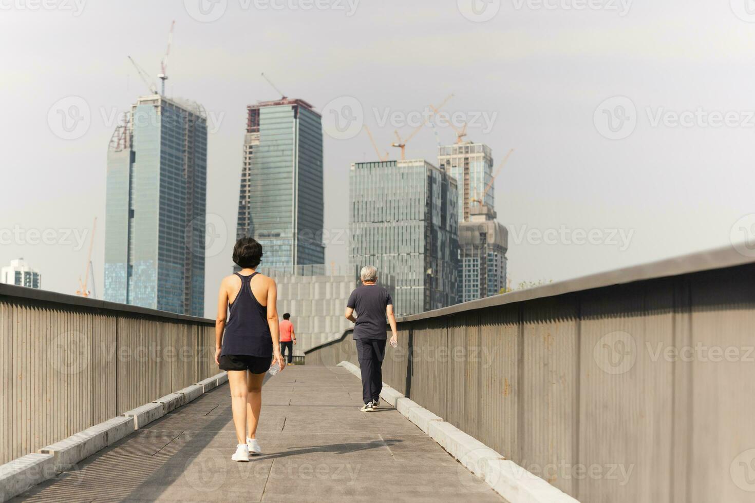 Frau Übung Gehen auf das Brücke Hand halten Flasche Wasser mit Stadt Gebäude Sicht. foto