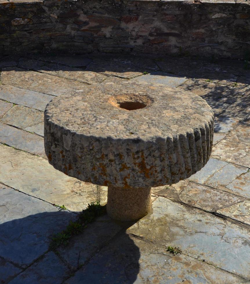 runder antiker Steintisch, der einen Innenhof eines alten Gebäudes schmückt foto