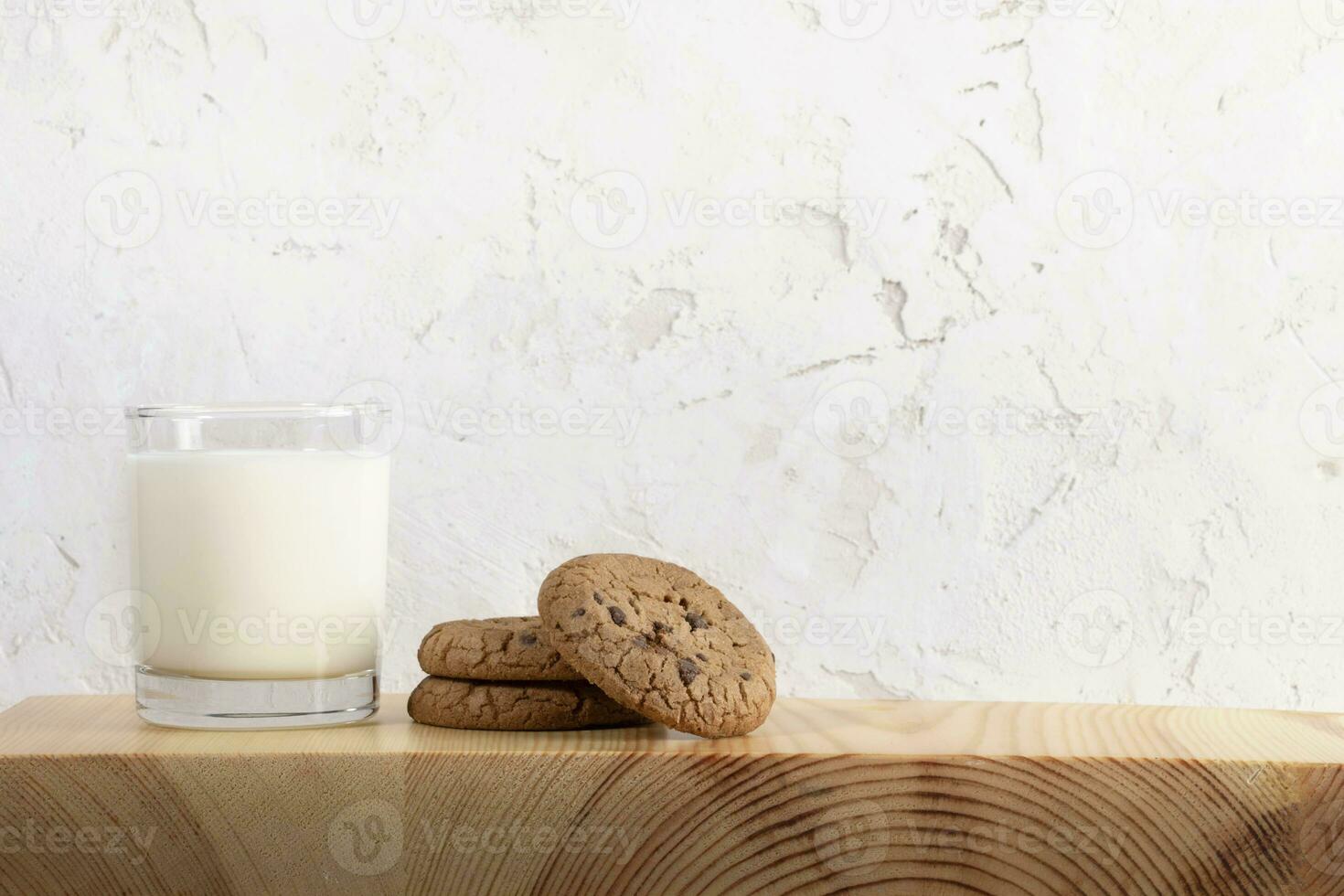 Glas von Milch und Kekse auf hölzern Portion Planke, Weiß texturiert Mauer wie Hintergrund. Kopieren Raum. foto