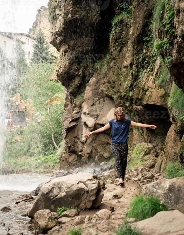 kleiner Mensch, der am schönen Bergwasserfall beobachtet foto