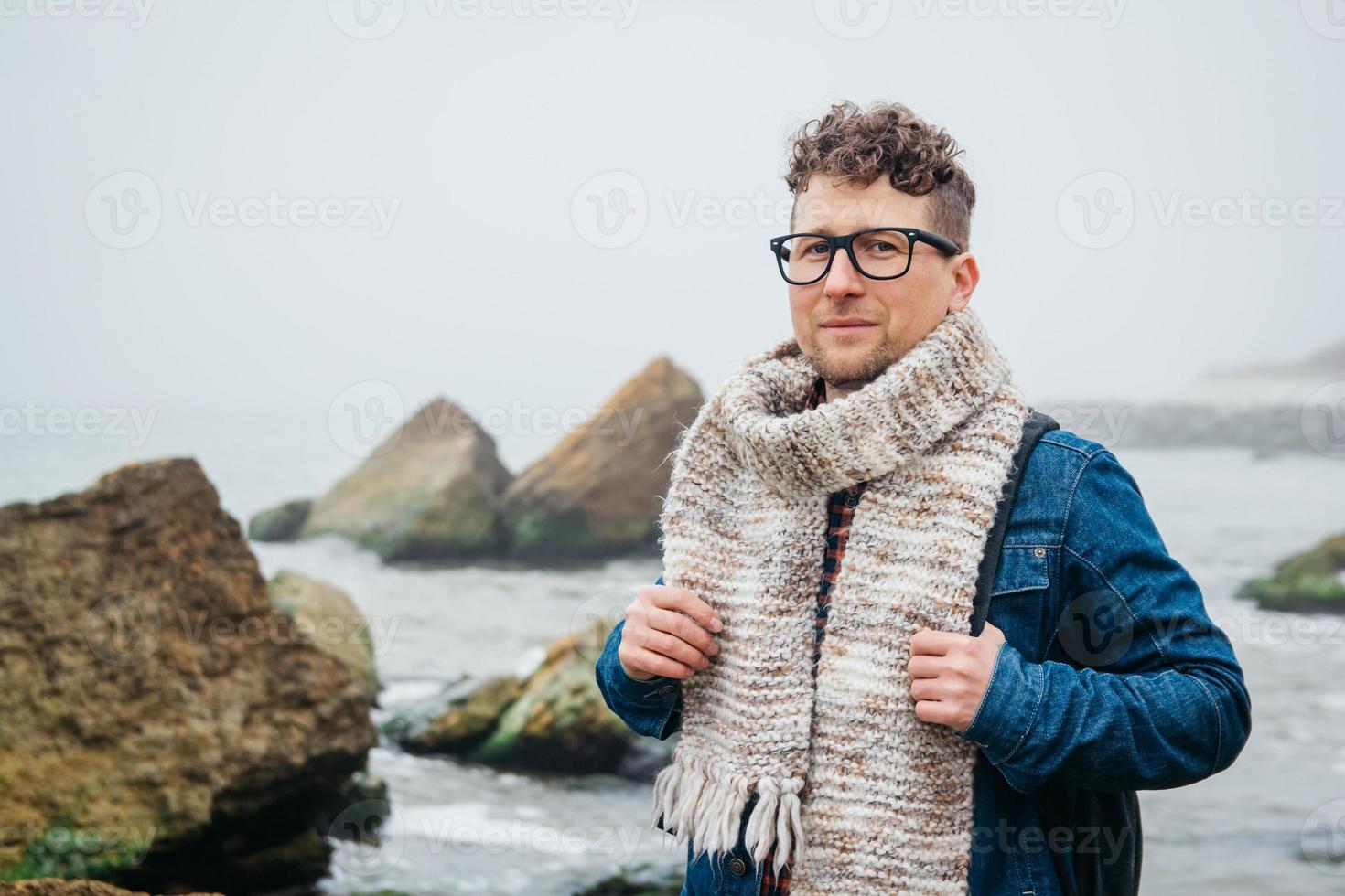 Mann mit Rucksack steht auf einem Felsen vor einem schönen Meer foto