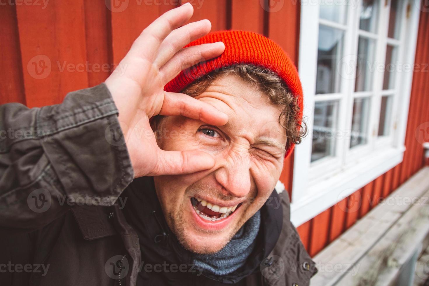 Porträtreisender sitzt in der Nähe des roten Holzhauses foto