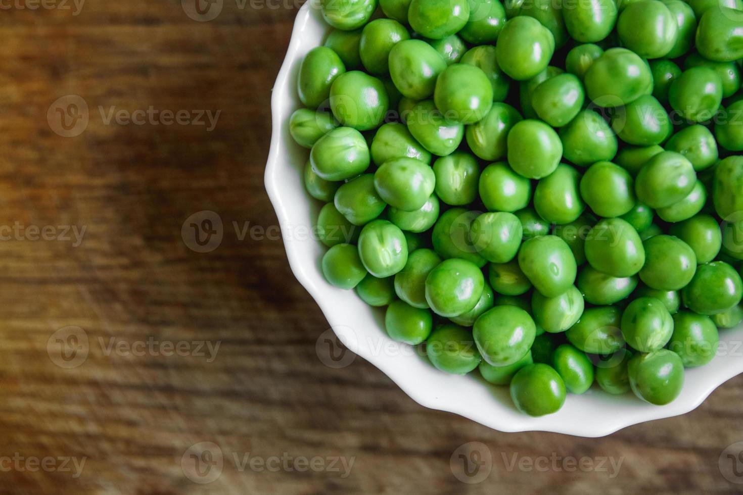 frische grüne Erbsen in einem weißen Teller auf Holzuntergrund foto