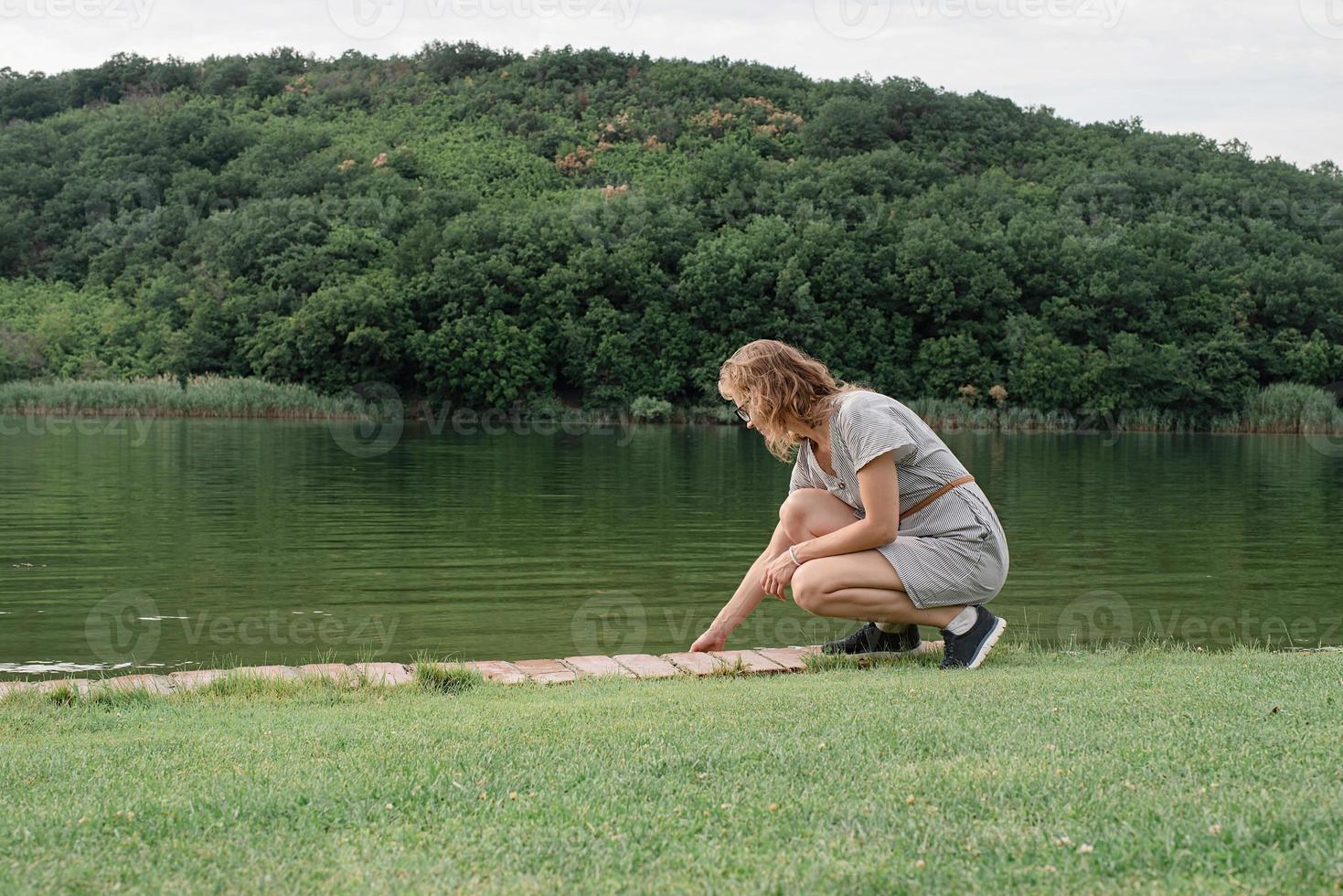 Frau sitzt am See und schaut weg foto