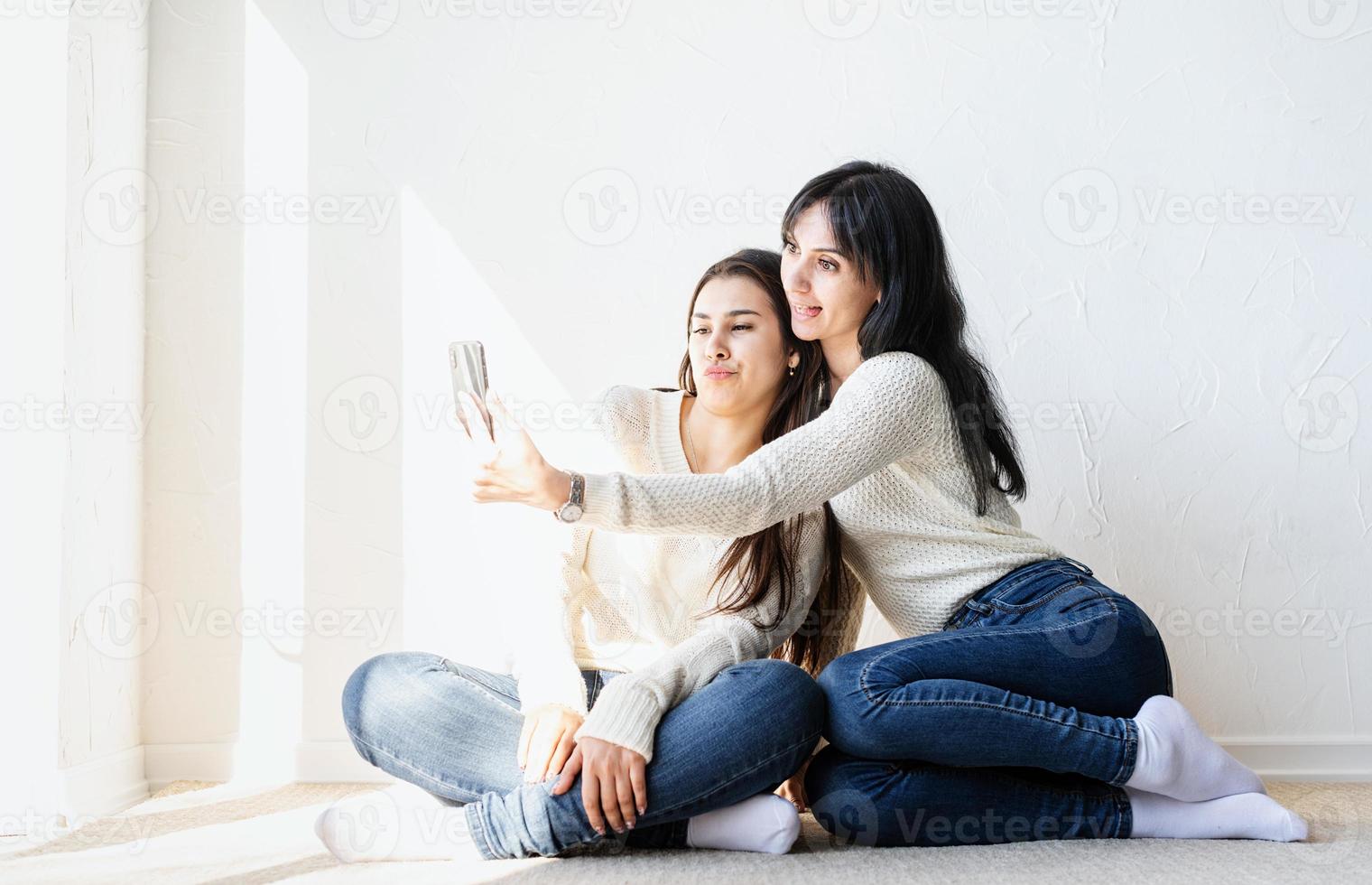 Zwei schöne Frauen machen Selfie auf dem Handy und machen lustige Gesichter foto