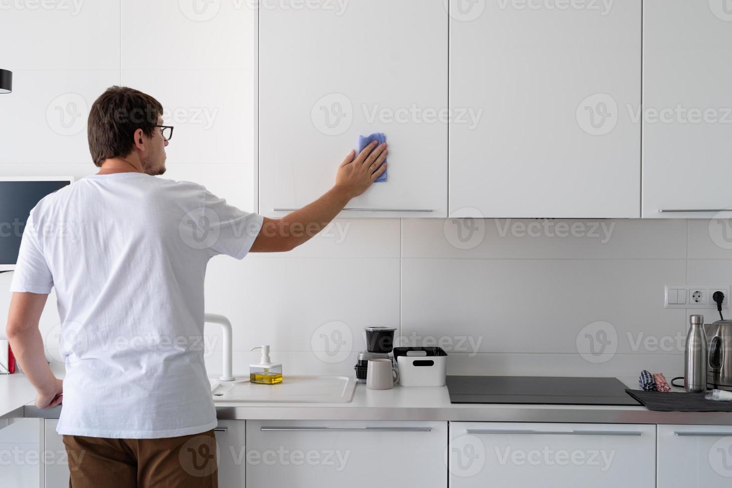 Mann putzt die Küchenoberflächen foto