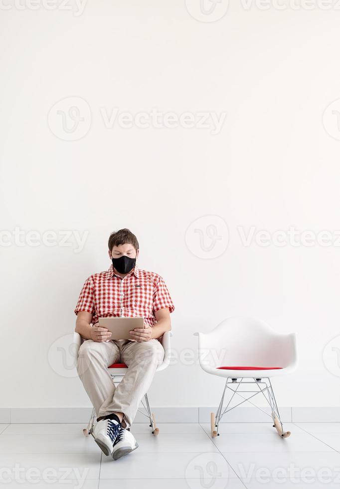 junger Mann in Schutzmaske, der online studiert und soziale Distanz einhält foto